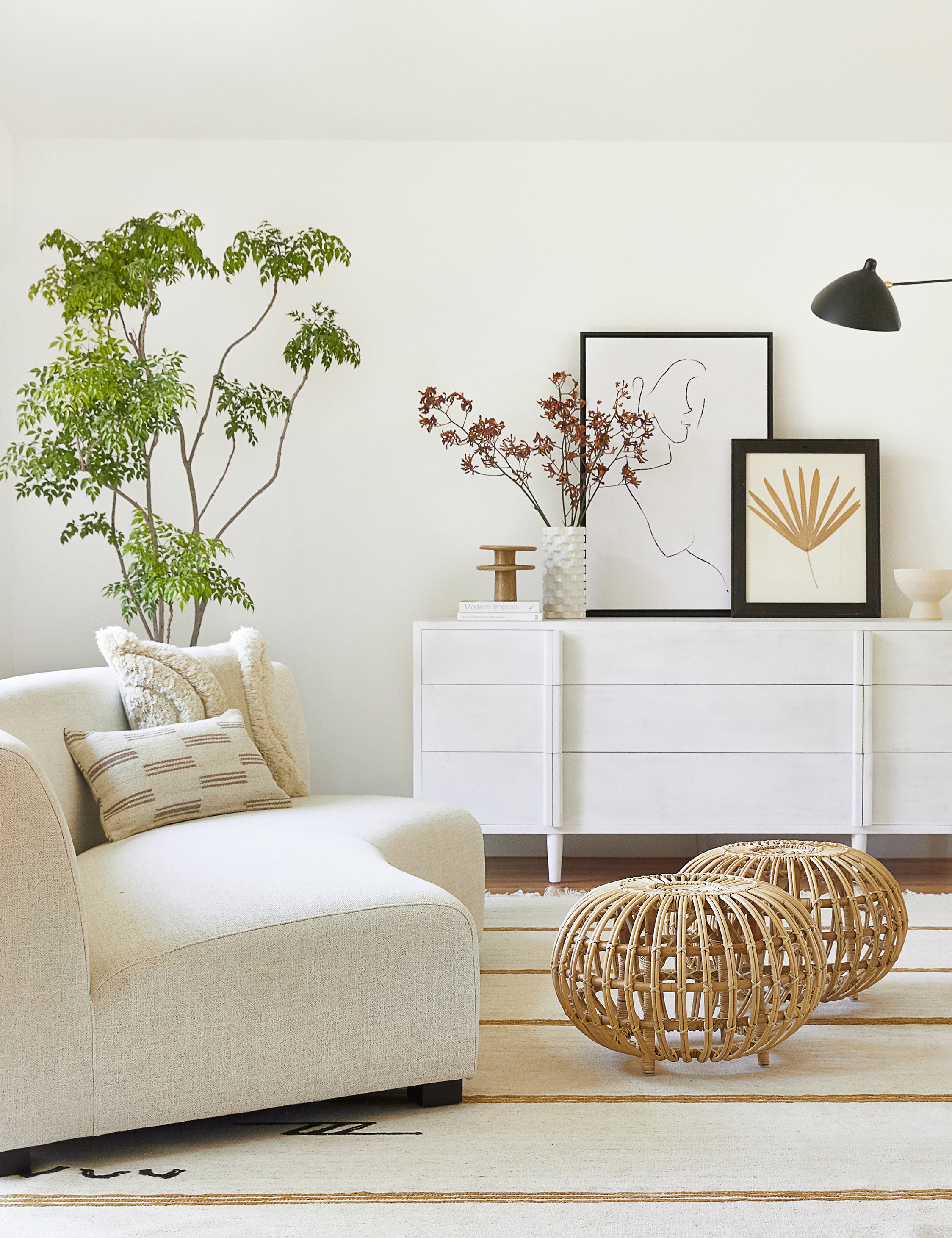 The Iconic Stripe Rug lays in a living room with a woven coffee table, an ivory sofa, and a white sideboard