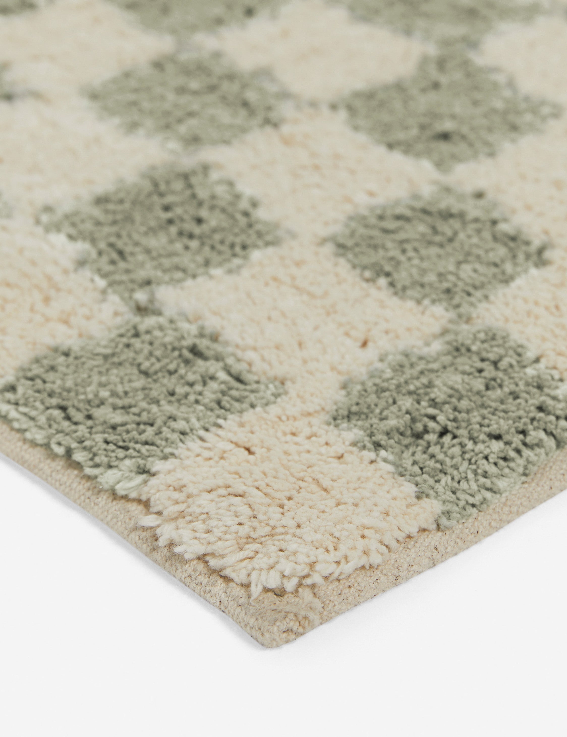 Close up corner view of the Two-tone checkerboard bath mat by Sarah Sherman in lichen green