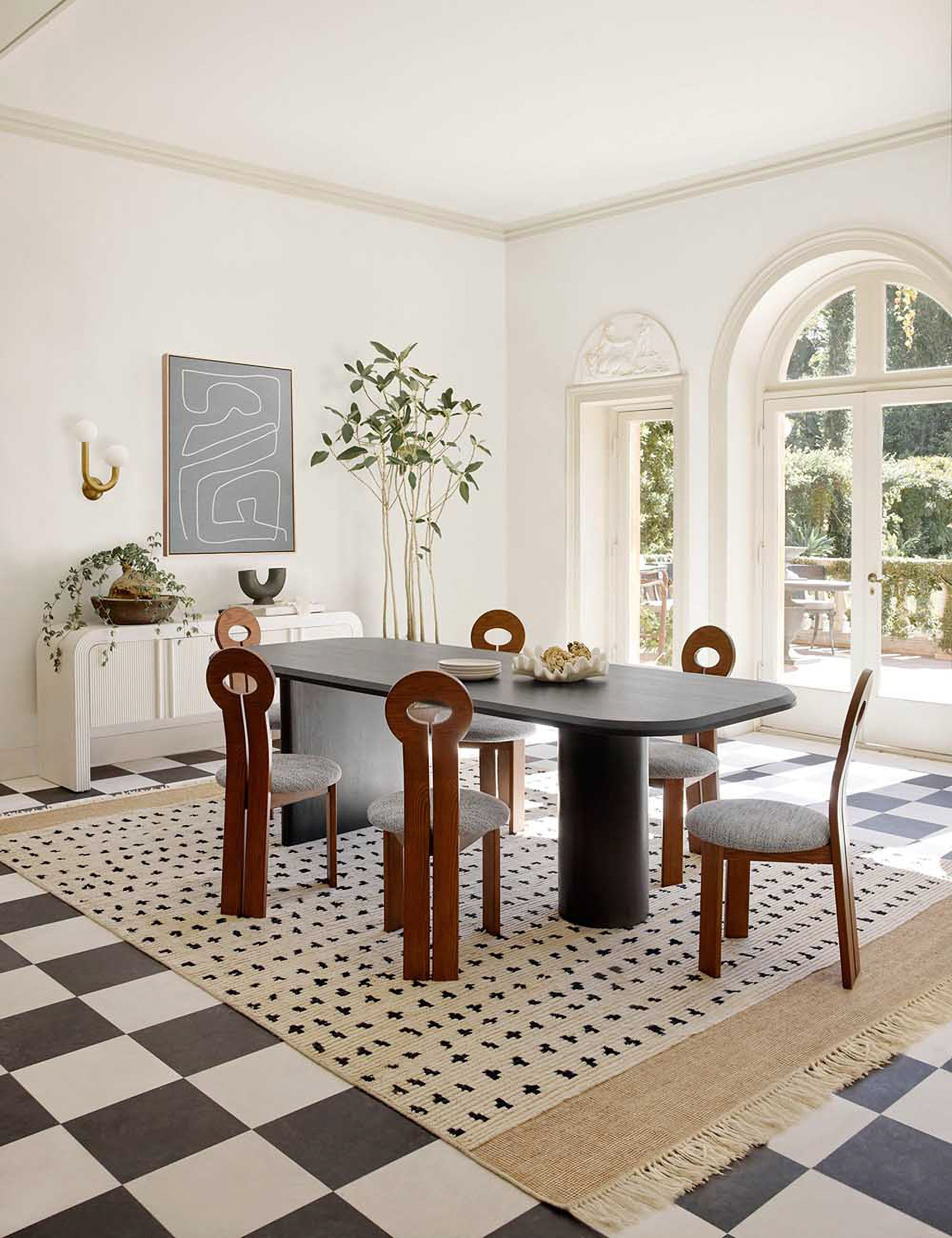 Archer Black Rectangular Dining Table sits in dining room atop a dotted rug, a checkerboard floor, and surrounded by sculptural chairs