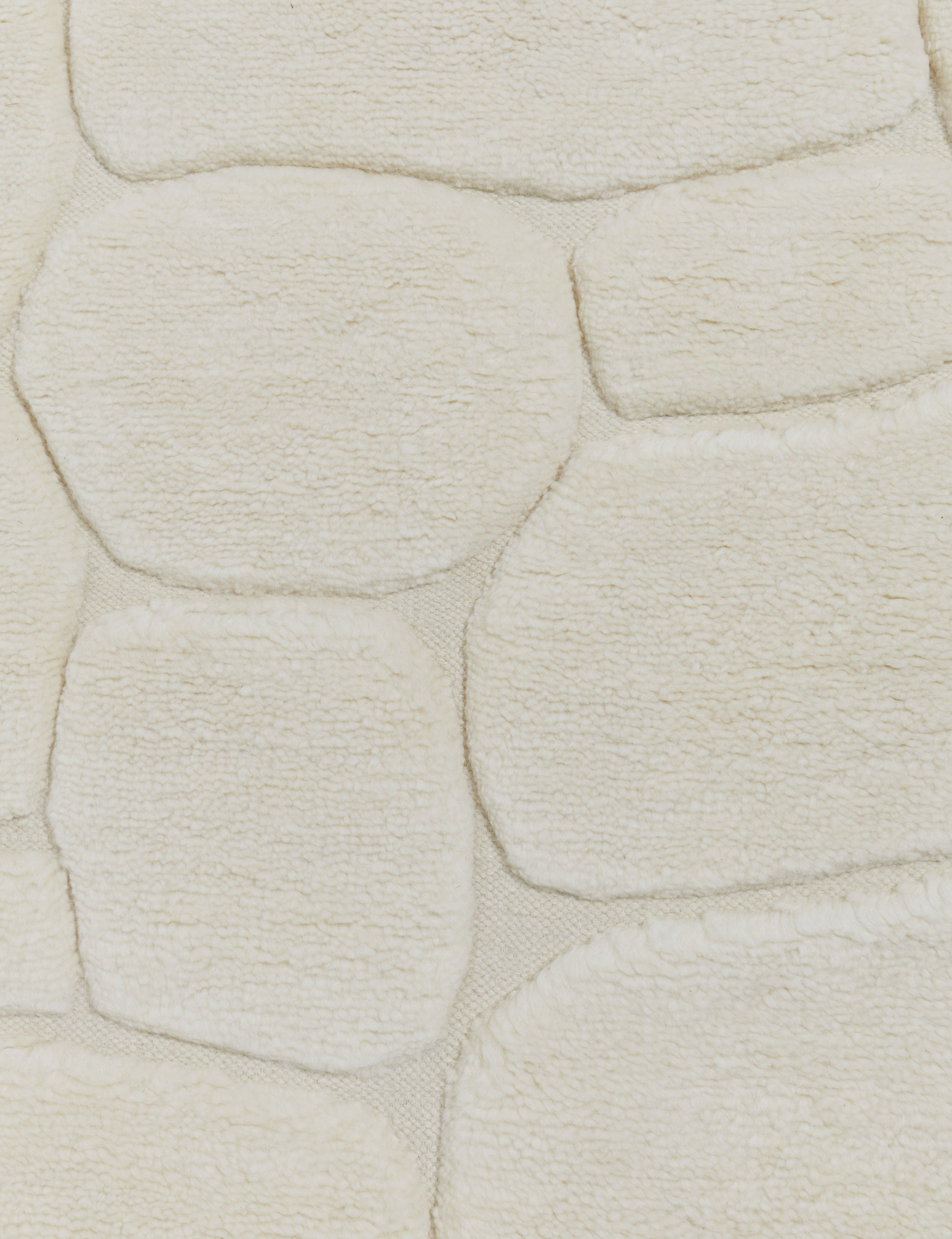 Close up view of the Kivi raised cobblestone pattern fringe wool area rug