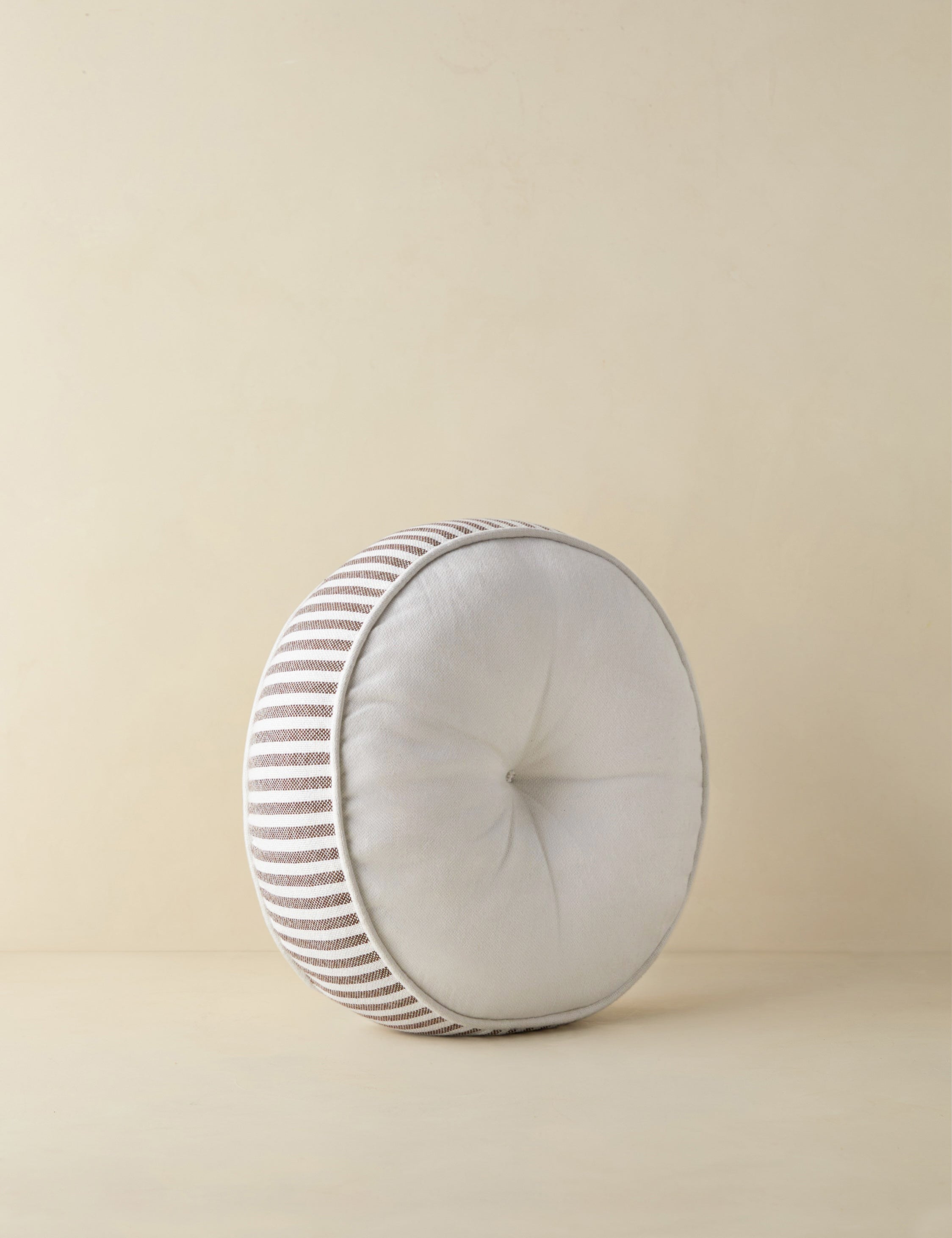 Angled view of the Littu Indoor / Outdoor Striped Disc Pillow by Sarah Sherman Samuel in Brown