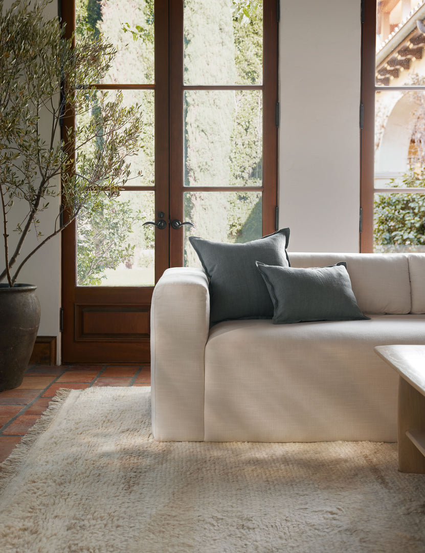 #color::dusty-blue #style::square #fill type::with-feather-down-insert #fill type::pillow-cover-only | The arlo Dusty Blue flax linen pillow in its lumber and square sizes sit together on a natural linen sofa in a room with tall french doors 