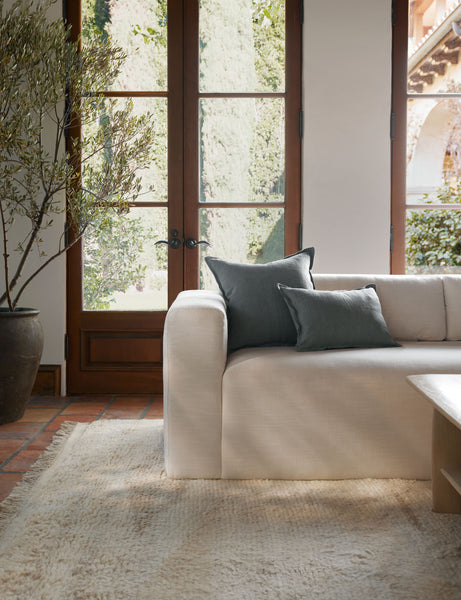 #color::dusty-blue #style::square #fill type::with-feather-down-insert #fill type::pillow-cover-only | The arlo Dusty Blue flax linen pillow in its lumber and square sizes sit together on a natural linen sofa in a room with tall french doors 