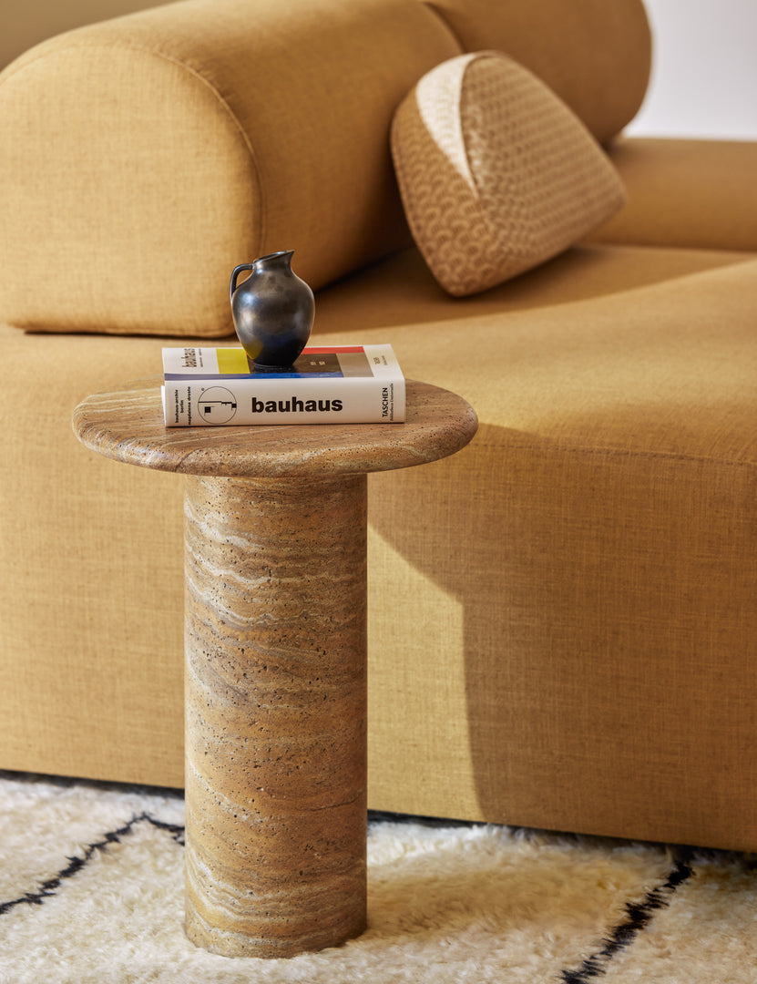 #color::Canyon-Faux-Travertine | Mona round stone drink table styled next to a modular armless sofa.