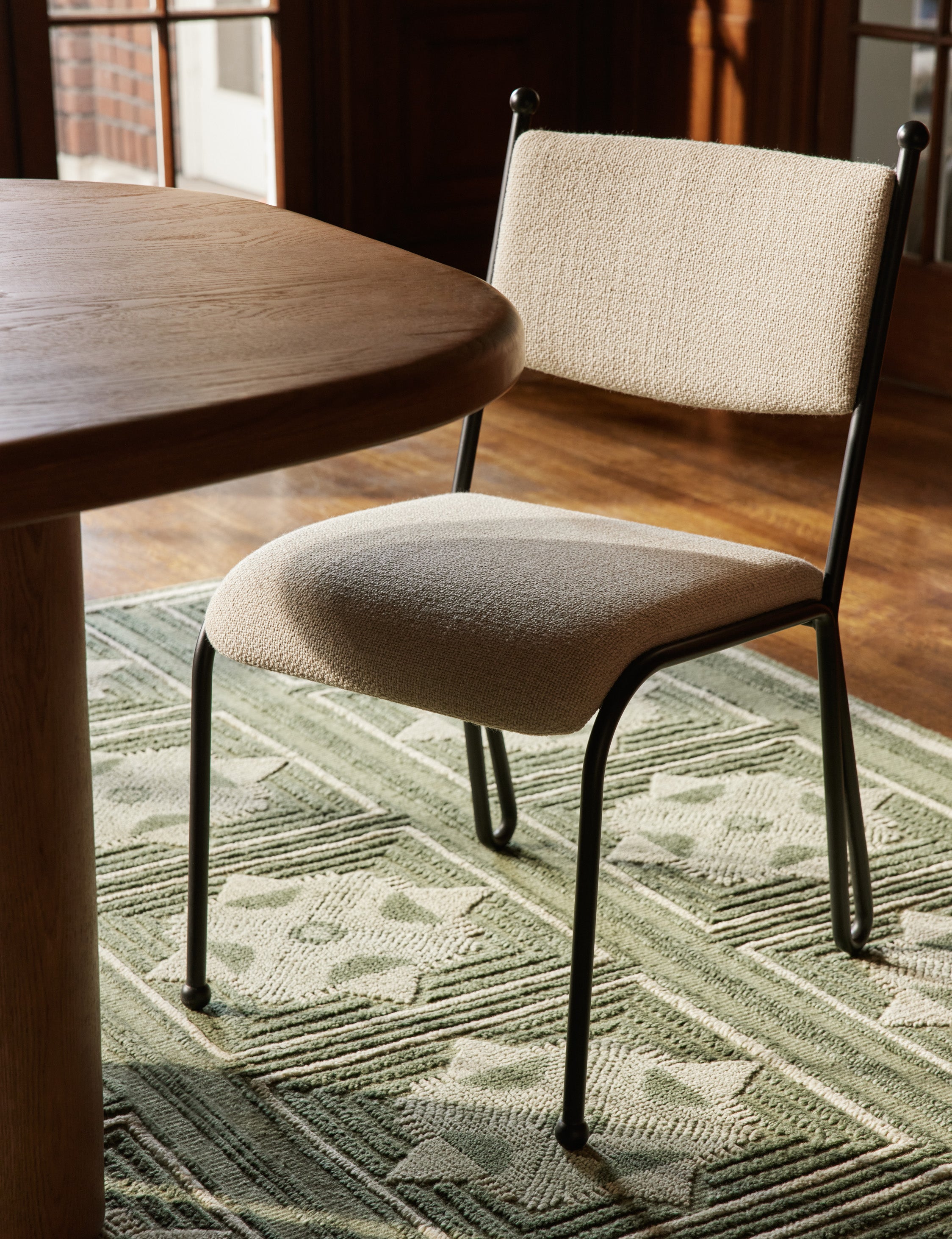 Fidia curved metal silhouette dining chair by Aimee Song next to a dining table