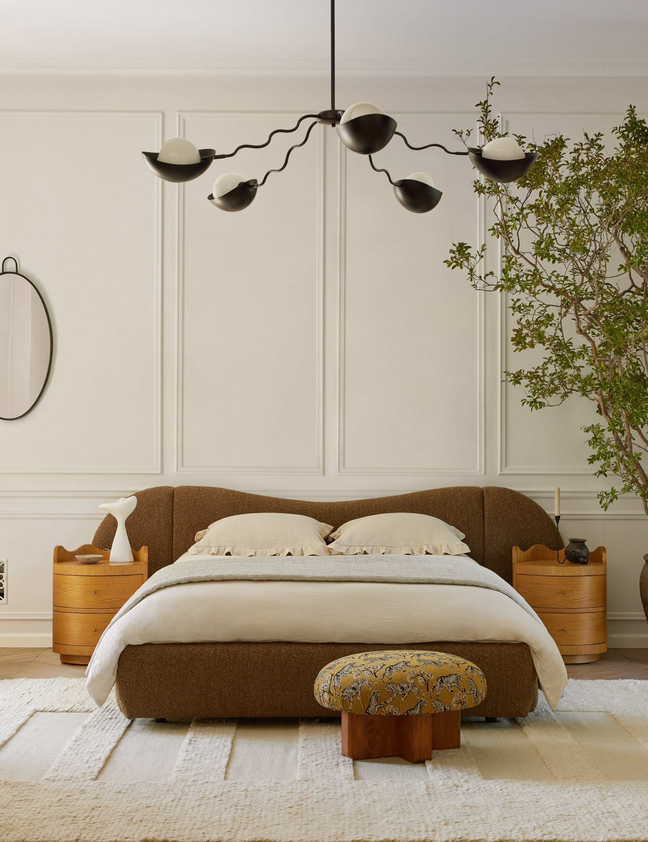 Kukka large modern wavy arm chandelier in bronze hanging in a bedroom over the bed