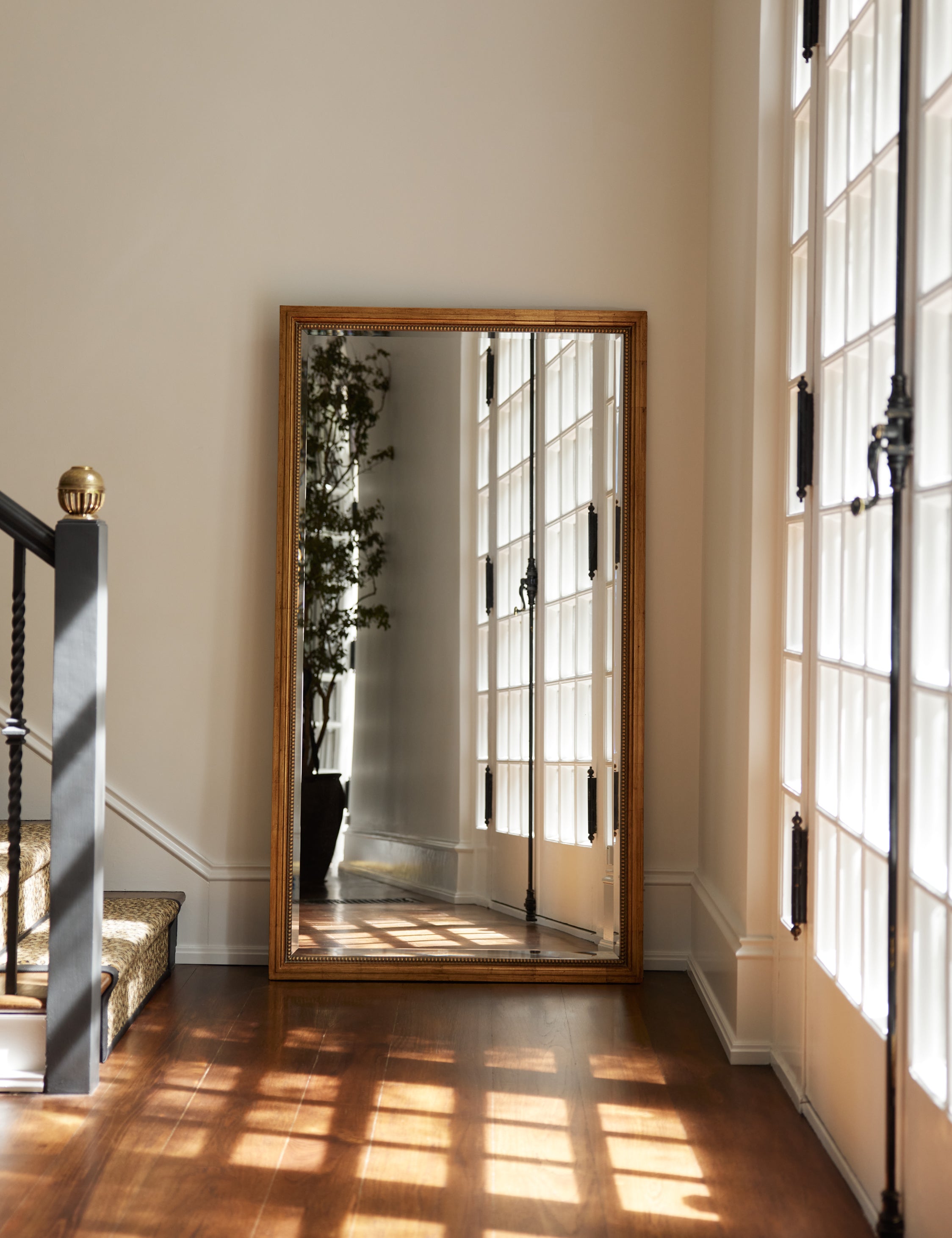 Corinne textural gold epoxy resin frame floor mirror leaning against a wall in an entryway.
