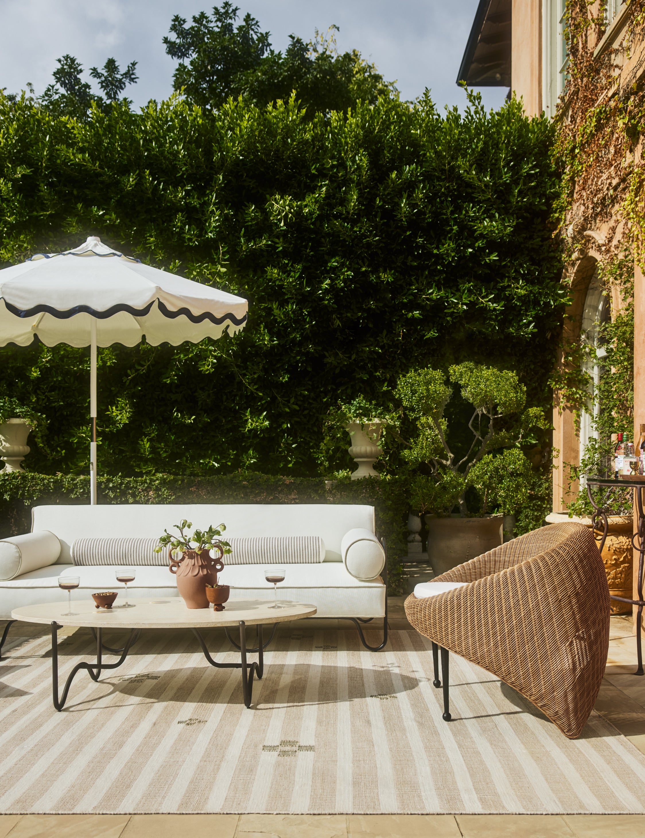 Outdoor patio space featuring the Peggy sculptural iron frame and white cushion outdoor sofa.