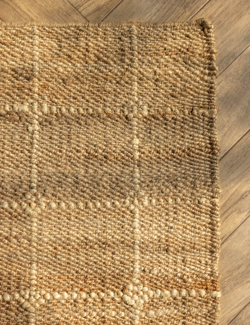#color::natural #size::2-6--x-8--runner #size::3--x-5- #size::4--x-6- #size::5--x-8- #size::6--x-9- #size::8--x-10- #size::9--x-12- #size::10--x-14- #size::12--x-15- | Close up of the corner of the Beddow Flatweave Jute Grid Rug by Jake Arnold.