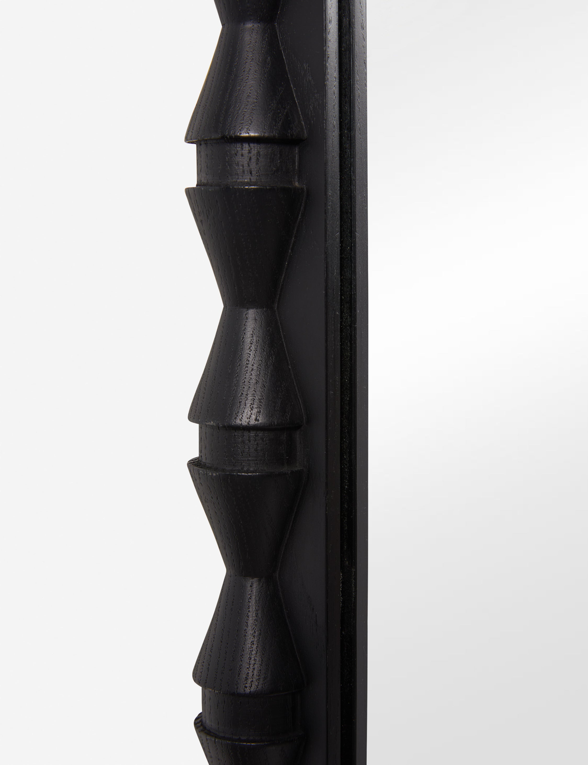 Close up of the frame details of the Topia arched carved wood frame floor mirror by Ginny Macdonald in black.