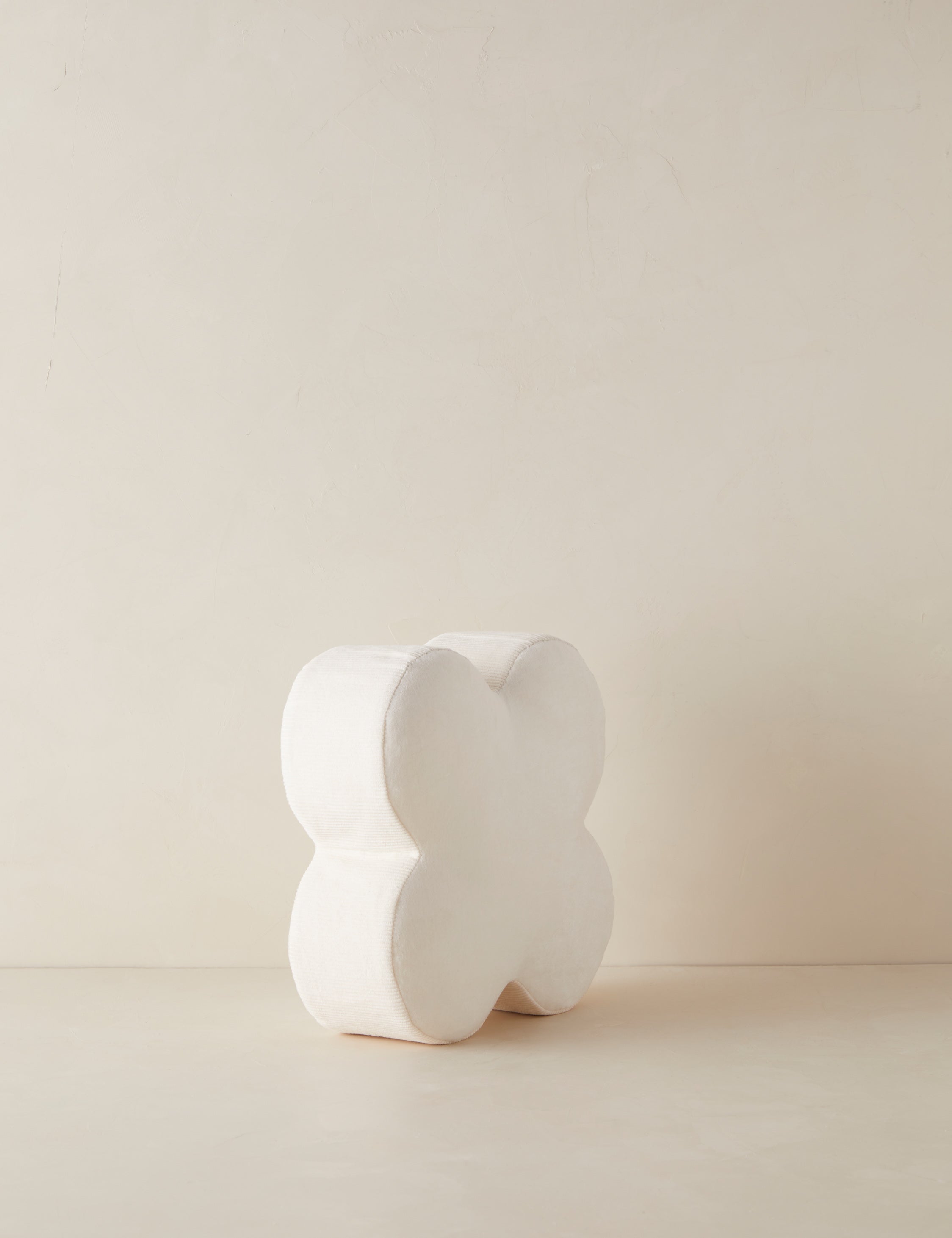 Angled view of the Velvet clover shaped accent pillow in ivory