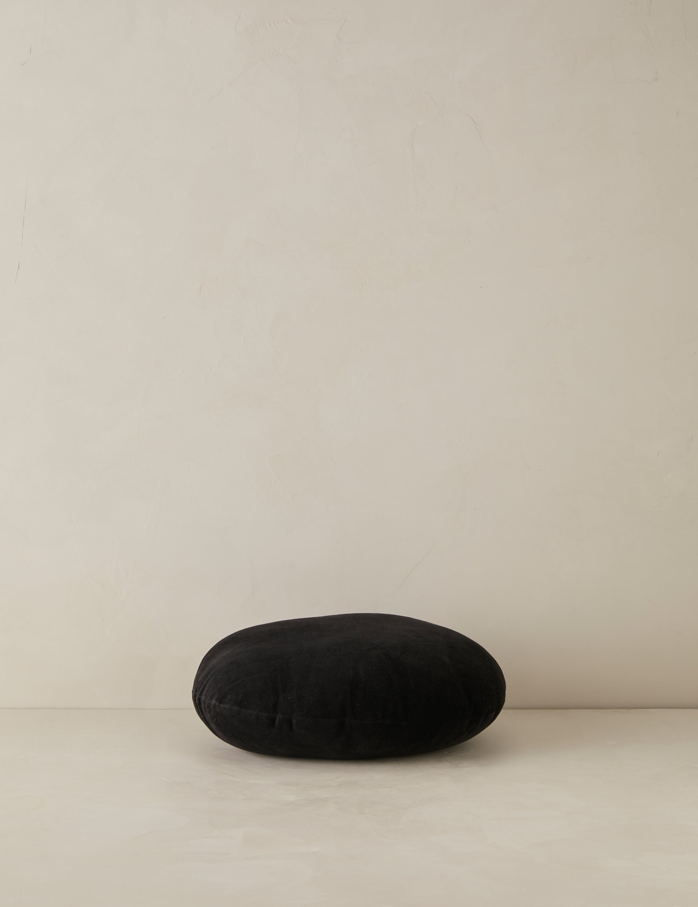 Velvet round accent pillow in black laying flat