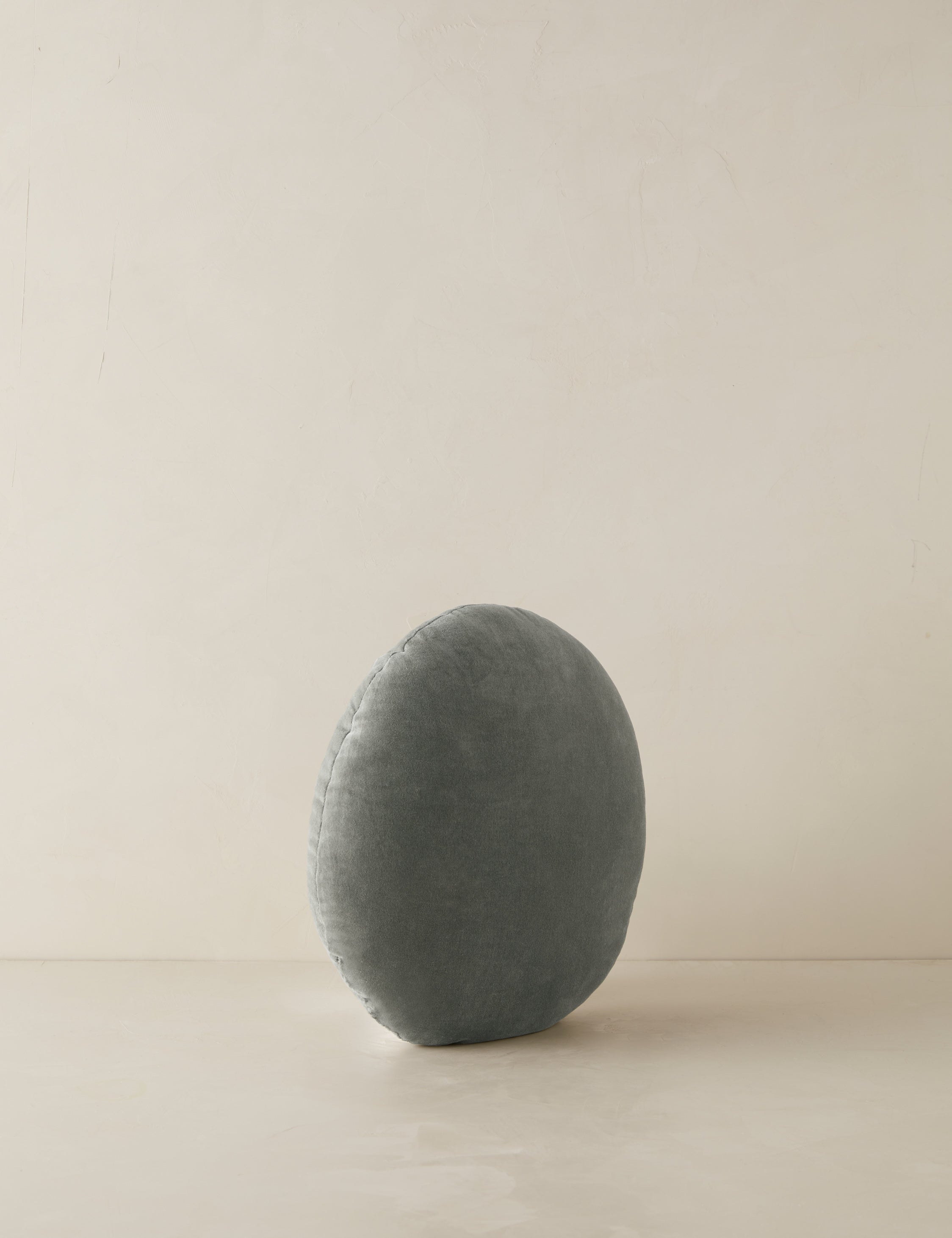 Angled view of the Velvet round accent pillow in lichen