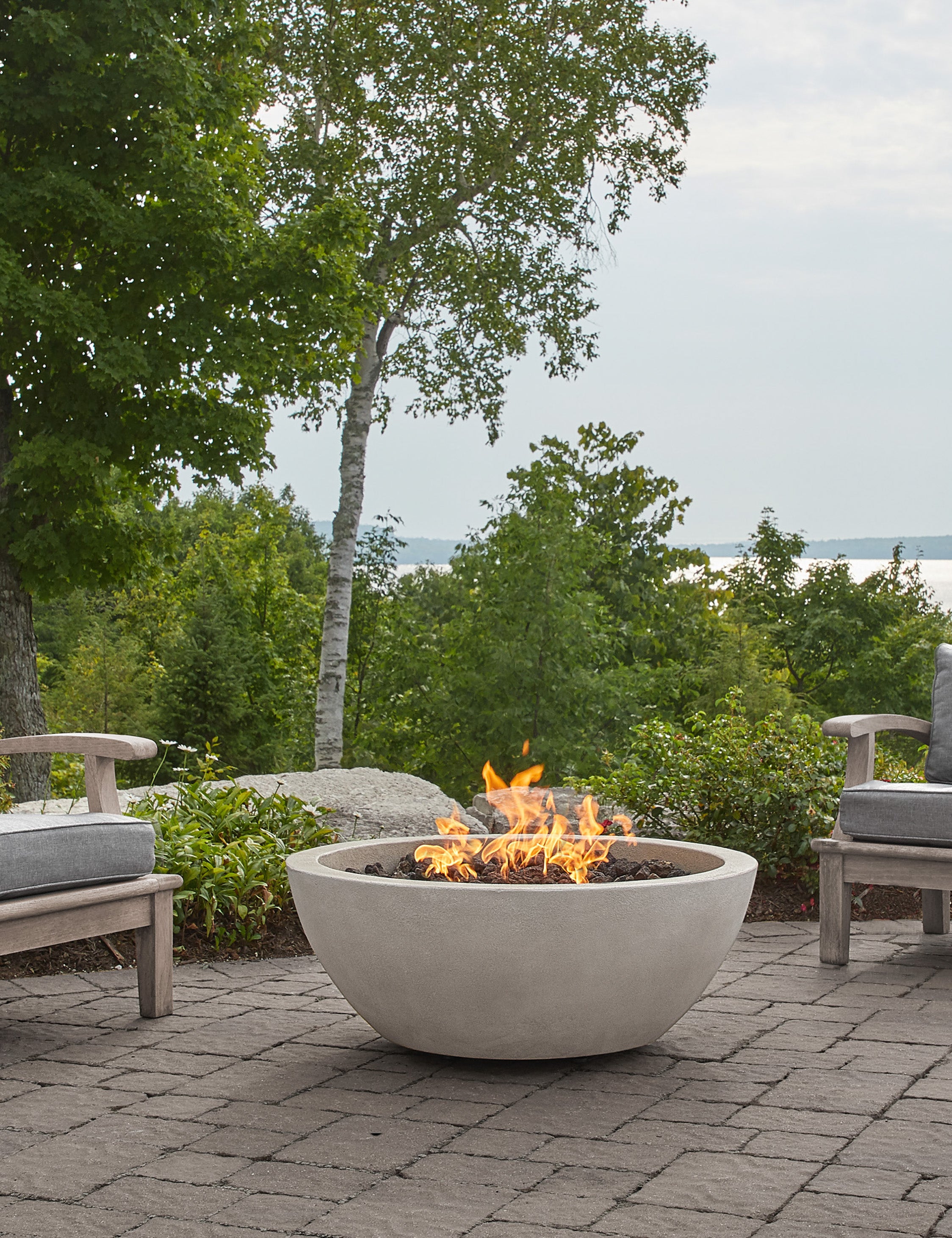 The Benno fog fire bowl sits in an outdoor space next to outdoor lounge furniture