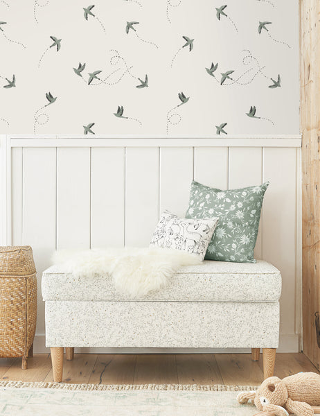 #color::blue | The Sparrow blue and white wallpaper by Rylee and Cru is in a bedroom above a white wooden paneled wall with a floral patterned bench and patterned throw pillows.