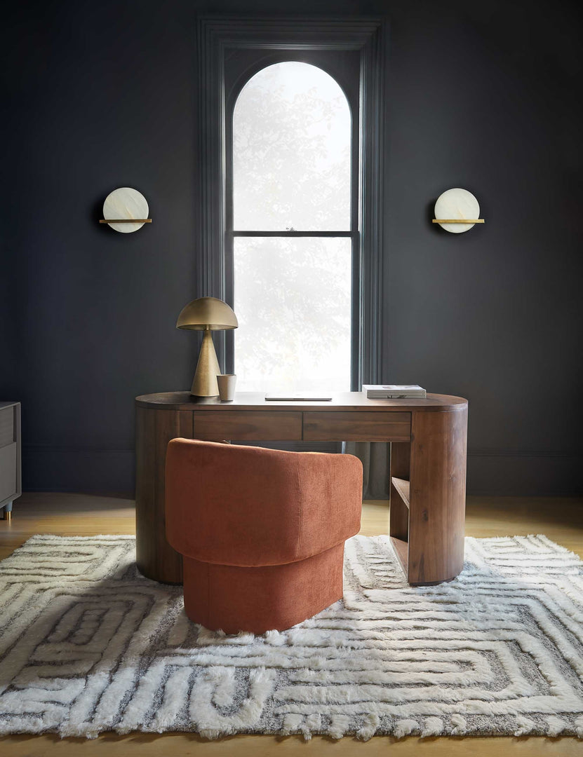 #size::6--x-9- #size::8--x-10- #size::9--x-12- #size::10--x-14- #color::rug #size::12--x-15- | The braeburn rug lays in an office with black walls and a narrow central window under a desk and a rust orange chair