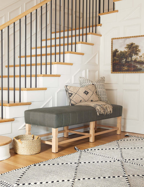 #color::loden | The ambleside loden gray linen bench sits by a staircase against white accented walls near a black and white patterned rug