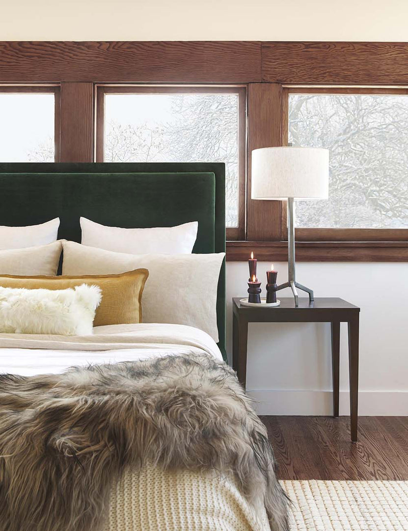 #color::marigold #style::extra-long #fill type::with-feather-down-insert #fill type::pillow-cover-only | The arlo marigold long lumbar pillow sits on an emerald green framed bed with ivory linens