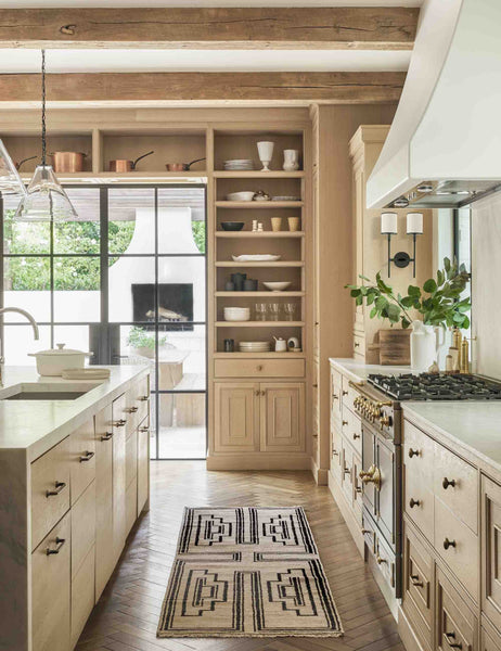 #size::2-6--x-8- | The Senna neutral hand-knotted wool area rug with black geometric pattern sits in a light wood kitchen.
