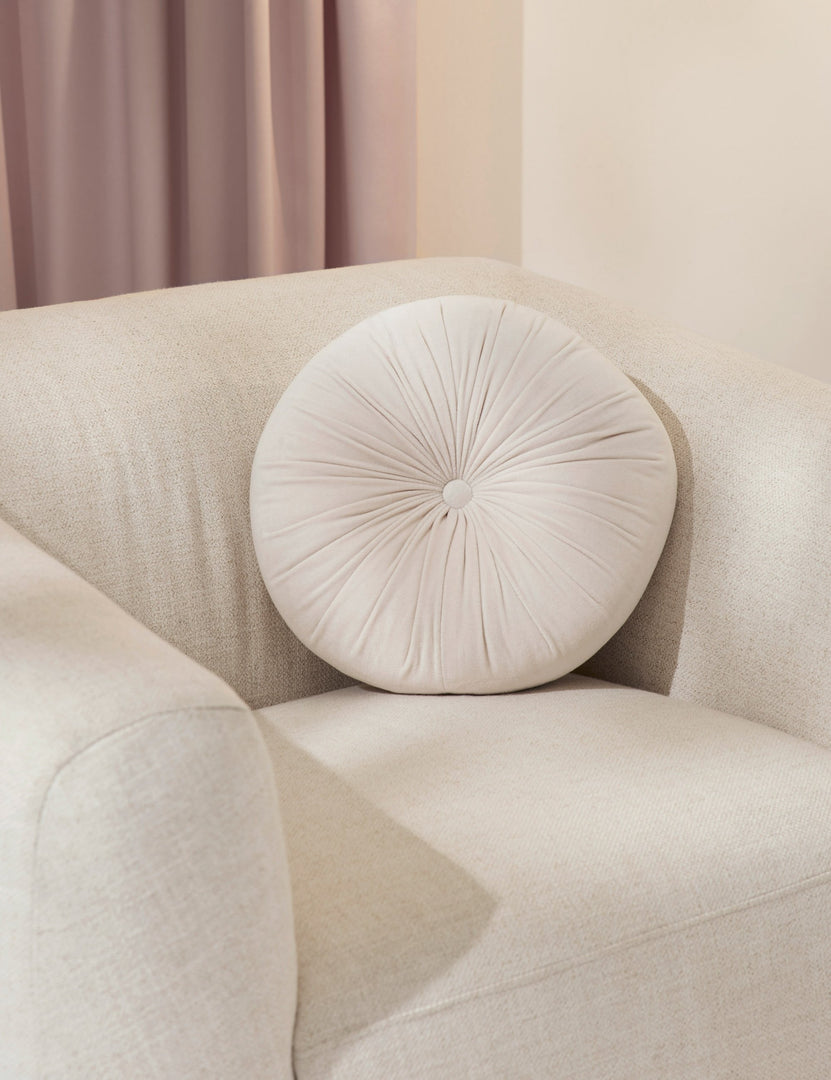 #color::oyster | The Monroe oyster white velvet round pillow sits on a white accent chair