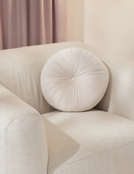 #color::oyster | The Monroe oyster white velvet round pillow sits on a white accent chair