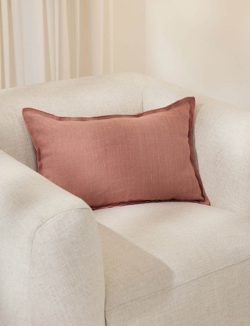 #color::terracotta #style::lumbar #fill type::with-feather-down-insert #fill type::pillow-cover-only | The arlo Terracotta lumbar pillow sits in a studio on a white linen accent chair