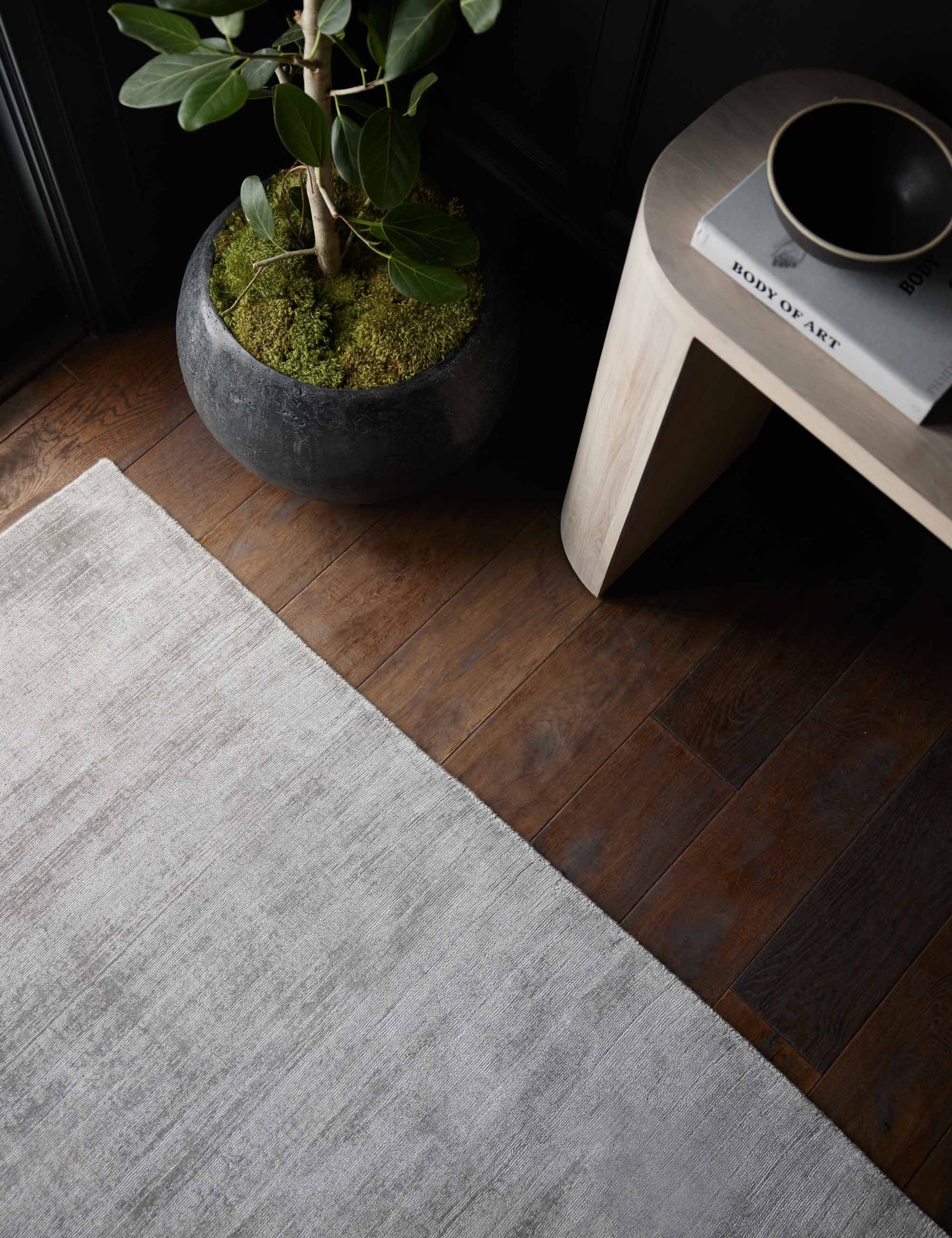 Close up view of the gray dylan rug laying next to a gray stone planter and a light wood sideboard