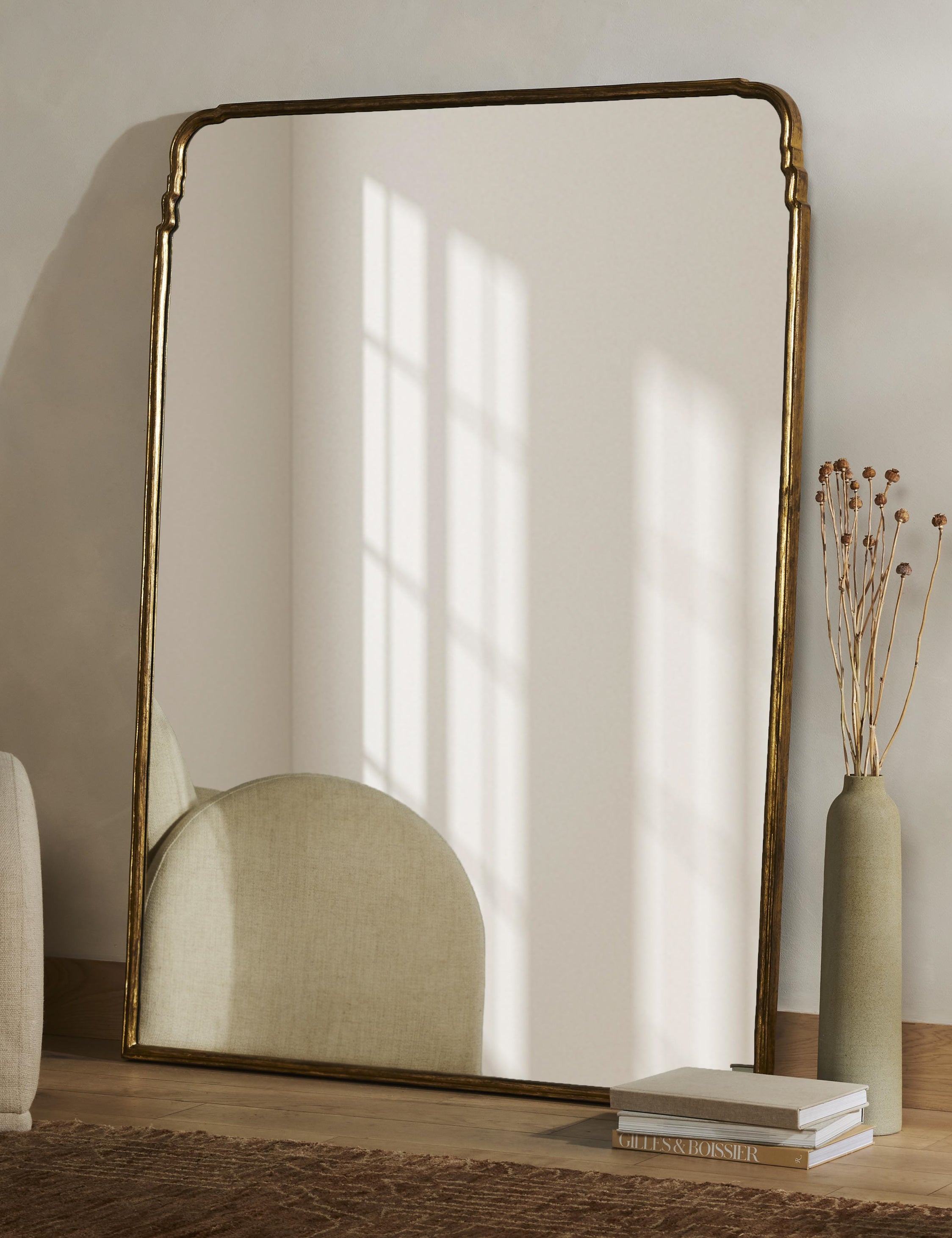Teresa thin gold-leaf frame floor mirror styled with a vase full of dried botanicals.