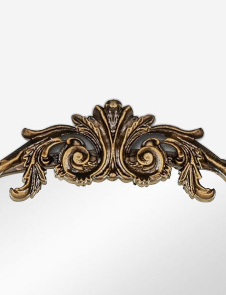 #color::gold | Detailed view of the traditional scroll detailing on the top of the Tulca arched gold mirror with flat bottom edge.