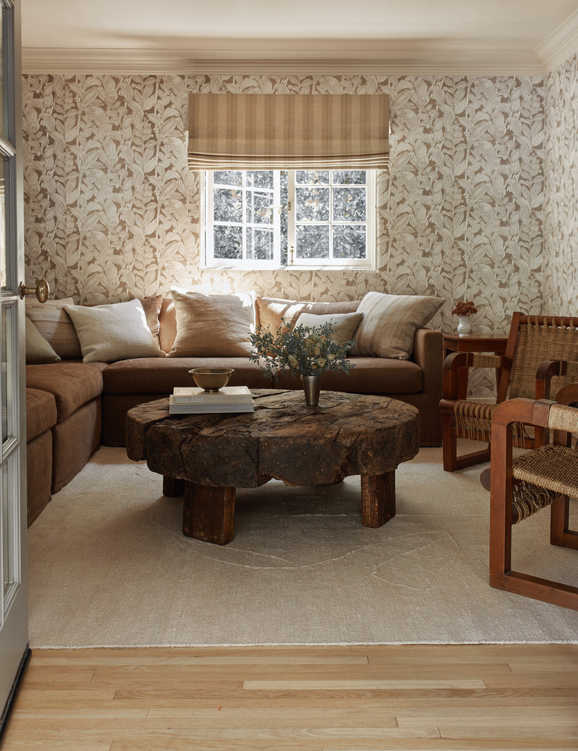 #size::2-6--x-8- #size::6--x-9- #size::8--x-10- #size::9--x-12- #size::10--x-14- #size::12--x-15- | The beachwood rug lays in an enclosed living room with botanical wallpaper under a brown sectional and round coffee table