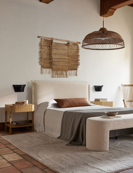 #color::burnt-orange #size::extra-long #fill type::with-feather-down-insert #fill type::pillow-cover-only | The arlo Burnt Orange long lumbar pillow sits on a natural linen framed bed below a jute chandelier and wall hanging