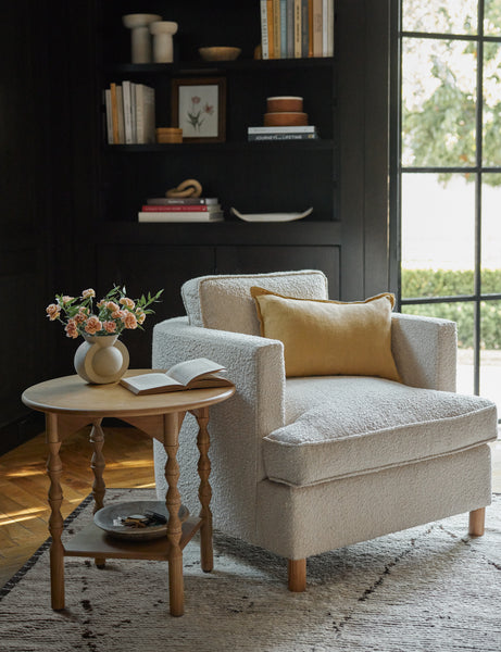 #color::marigold #style::lumbar #fill type::with-feather-down-insert #fill type::pillow-cover-only | The arlo marigold lumbar pillow sits on an accent chair next to a sculptural wooden side table