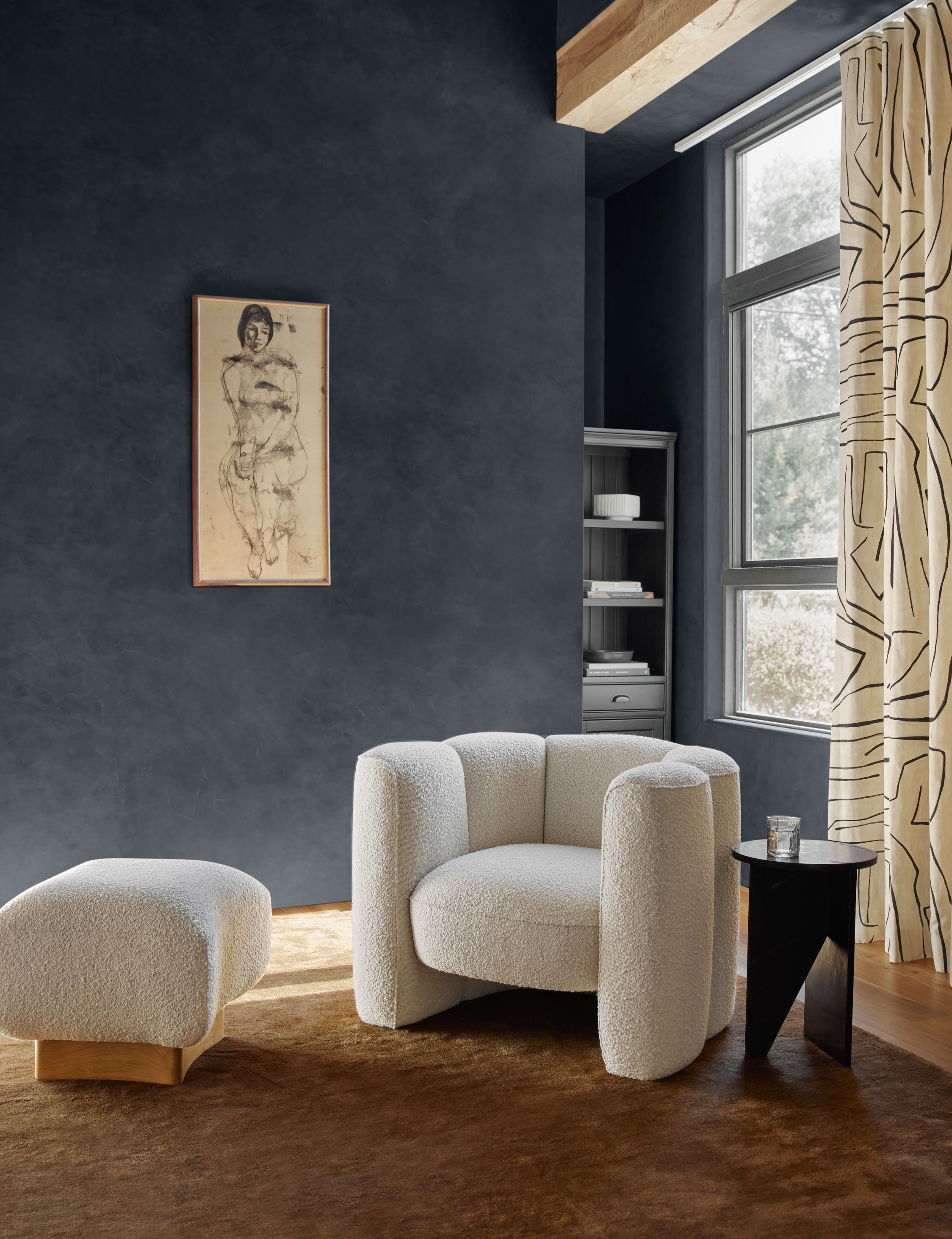 The Chiltern copper rug lays in a blue-toned room under a boucle accent chair, boucle ottoman, and black side table