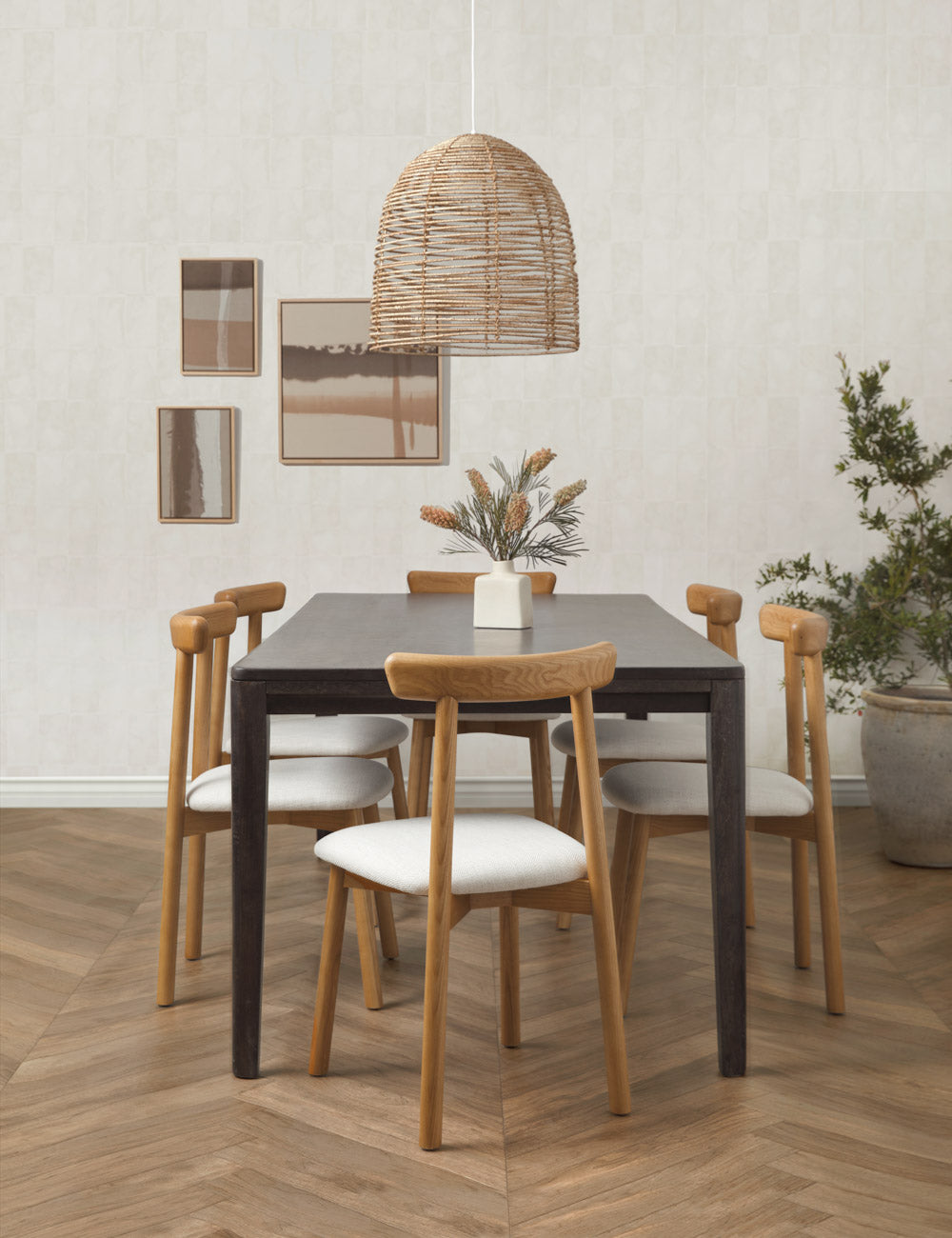 The Beehive jute woven pendant light is hung above a black rectangular dining table that is surrounded by six dining chairs