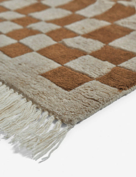 #color::ochre #size::2-6--x-8- #size::6--x-9- #size::8--x-10- #size::9--x-12- #size::10--x-14- #size::12--x-15- | Close-up of the corner and tassels on the Irregular brown checkerboard rug by Sarah Sherman Samuel