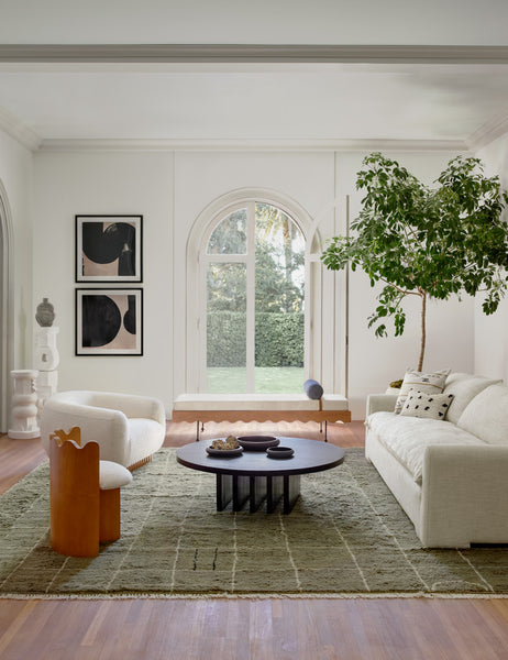 #color::natural-linen  | The Rupert natural linen sofa sits atop an olive green rug across from a round coffee table and a boucle accent chair