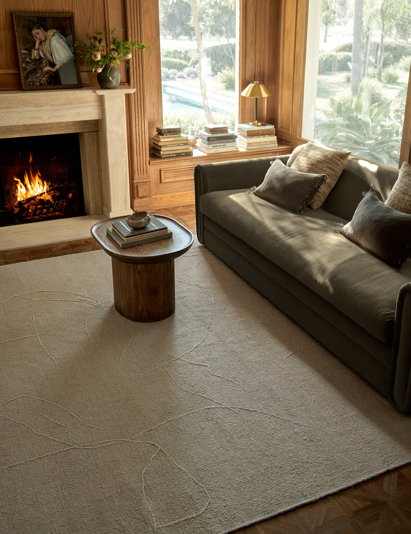#size::2-6--x-8- #size::6--x-9- #size::8--x-10- #size::9--x-12- #size::10--x-14- #size::12--x-15- | The beachwood rug lays in a dark living room with wooden walls under a wooden side table and a green velvet sofa