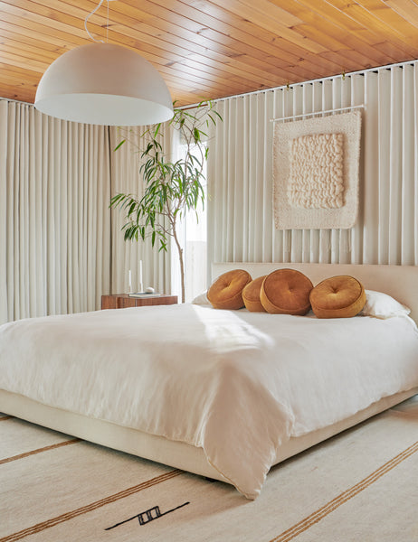 #color::amber | Four Velvet Disc amber Pillows by Sarah Sherman Samuel sit on a cream framed bed on natural linens in a bedroom with curtained walls