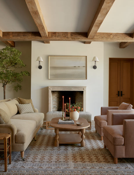 #showall::39867235795043 | Two Hayden double-armed black sconce lights hang on both sides of a landscape painting in a living room with warm-toned furniture