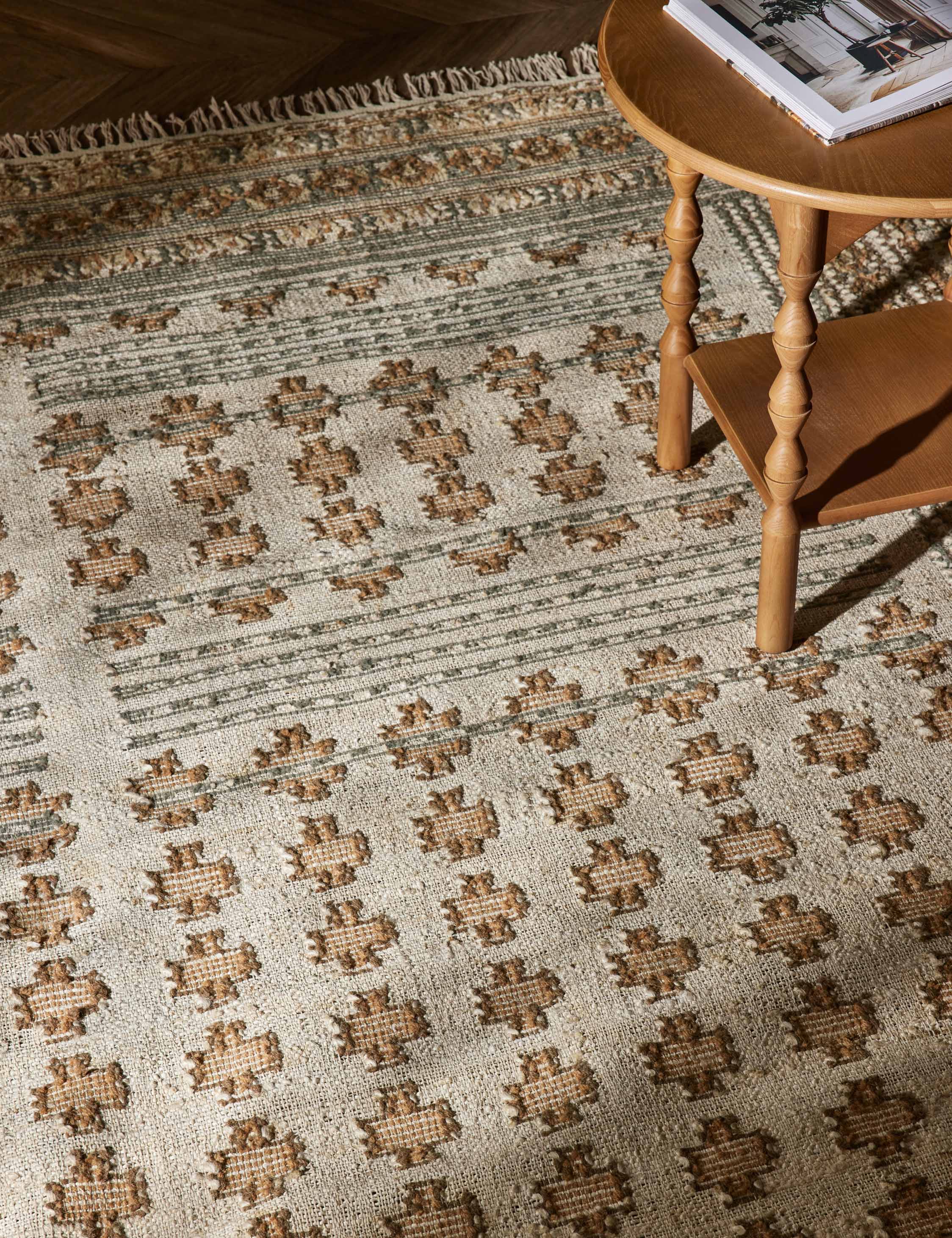 Close-up of the Keziah slate rug under a round side table with sculptural legs