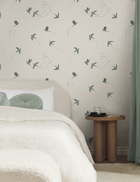 #color::blue | The Sparrow blue and white wallpaper by Rylee and Cru is in a bedroom with a wooden bedside table, a natural upholstered bed with blue throw pillows and curtains as accents.