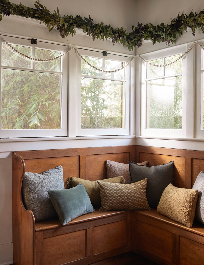 #color::conifer #style::square #fill type::with-feather-down-insert #fill type::pillow-cover-only | The arlo conifer gray pillow sits in a festive nook on a wooden corner bench