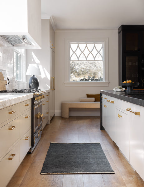 #color::indigo #size::3--x-5- #size::2--x-3- | The Heritage indigo runner rug lays in a kitchen with white cabinetry, gold hardware, and marble countertops 