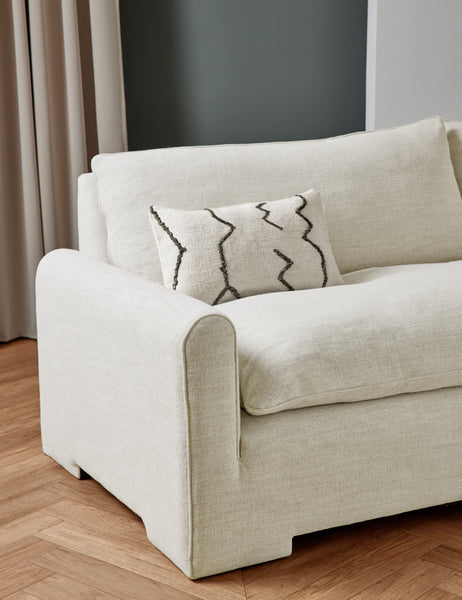 #color::natural-linen | The Rupert natural linen sofa sits in a studio room with an ivory flatweave pillow with black accents sitting atop it