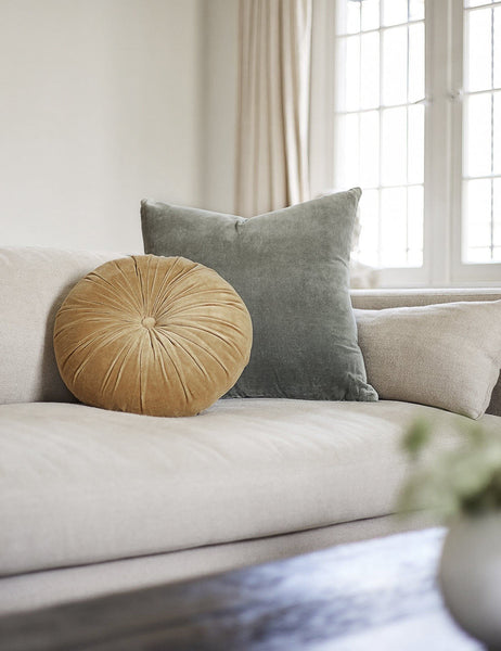 #color::moss #style::square  #fill type::with-feather-down-insert  #fill type::pillow-cover-only |   Charlotte Moss Green Square Velvet Pillow sits on a linen couch with a yellow disc velvet pillow