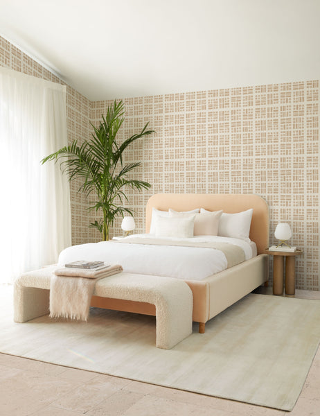 #showall::43011499786339 | The Tate cream boucle upholstered bench sits in a plush pink and white bedroom at the end of a pink velvet bed atop a soft ivory rug surrounded by patterned wall paper.