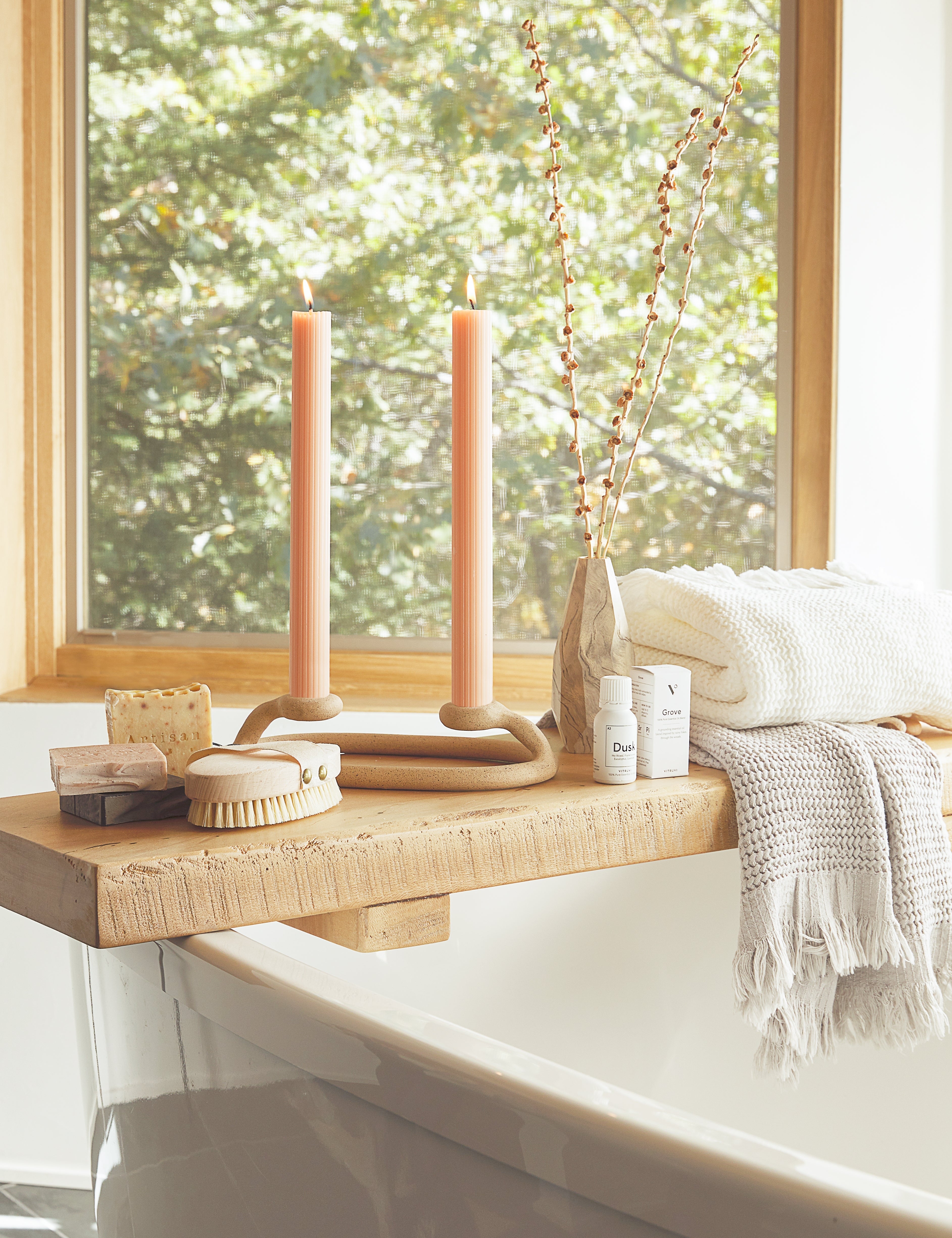 The Sherra white Waffle Towel by House No. 23 hangs on a wooden bath board with essential oils and bathroom accessories atop a white bath