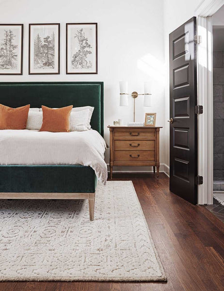 #color::burnt-orange #style::square  #fill type::with-feather-down-insert  #fill type::pillow-cover-only |   Two Charlotte burnt orange square pillows sit on an emerald velvet framed bed atop a white and neutral textured rug