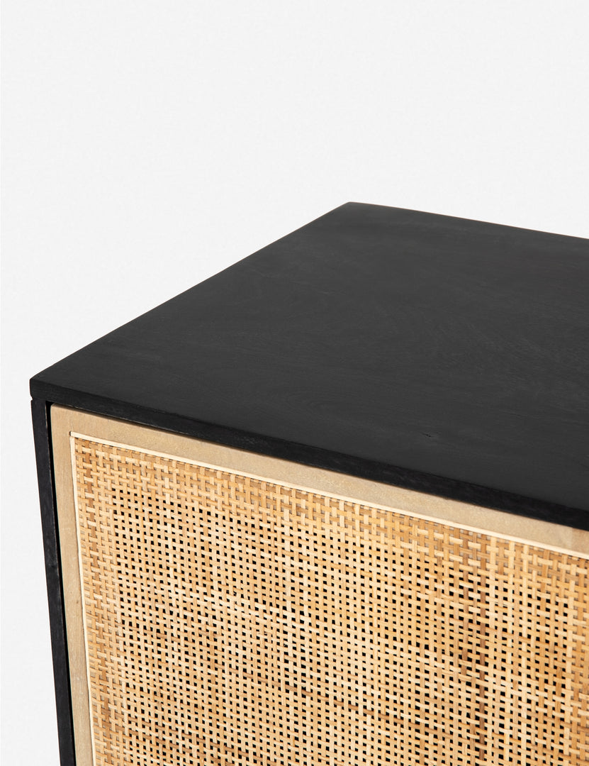 #color::black-and-natural | Detailed view of the upper corner of the Hannah black mango wood sideboard with  cane doors and an iron base.