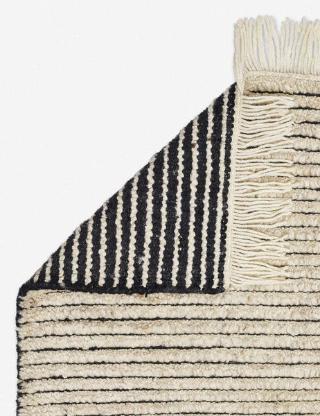#size::6--x-9- #size::8--x-10- #size::9--x-12- #color::black-and-natural #size::10--x-14- | The corner of the Kenzi black and natural rug folded over itself